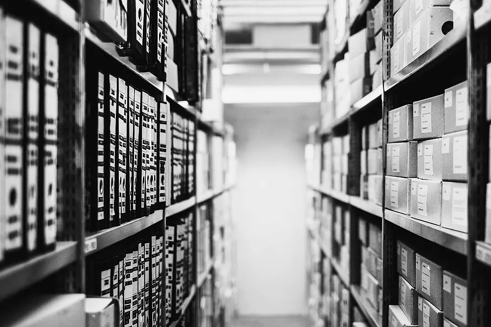 Labeled boxes filling steel shelving, rack after rack, in a storage room.
